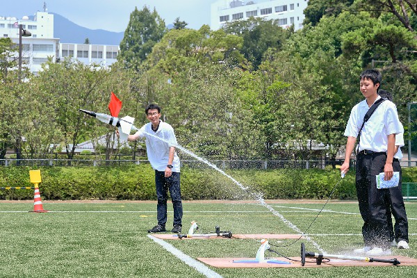 「高校対抗水ロケット大会」には、多くの高校が参加。水量や羽根の位置、発射角度など、先輩の大学生にアドバイスを受けながら工夫を凝らした高校生たち。青空の下、高く舞い上がる水しぶきに歓声を挙げていました。ちなみにこの日の最高記録は75ｍでした。