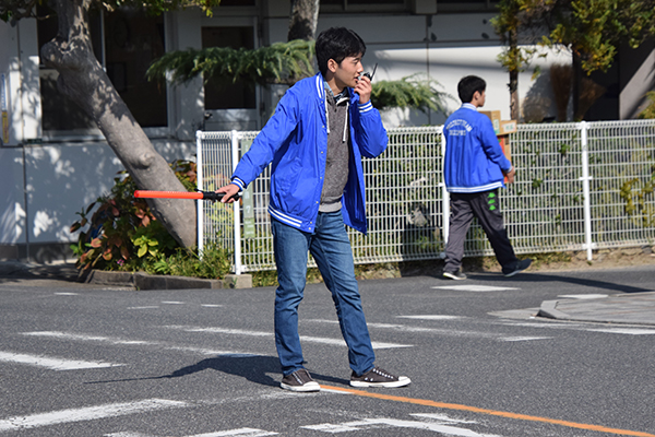 車で来場された方に、無線を使って仲間と連携を取りながらスムーズに駐車場誘導。「こんにちは！」と気持ち良く挨拶し、テキパキと案内していました。