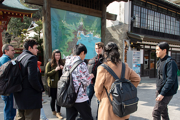 厳島神社の参拝を終えた後、宮島の案内板を前に次はどこへ向かうか相談する一行。「大元公園ってところに行ってみたいな」「それは遠いな」「大丈夫！早足だから」と話がまとまったようです。