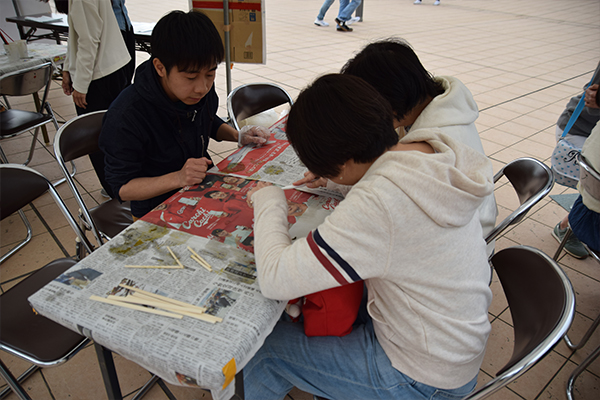 地球環境学科の学生で組織されるGREEN projectは、葉脈アート体験を実施。ヒイラギの葉を歯ブラシで磨き、取り出した葉脈に色を付けてラミネートする、しおりづくりを行いました。