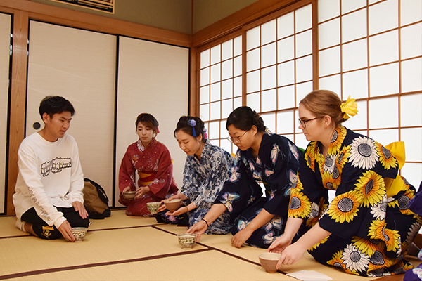 「お茶碗を手に持って右に回してください」と、茶道部員がお手本を見せながら作法を教えます。留学生たちも後に続き、見様見真似で実践。