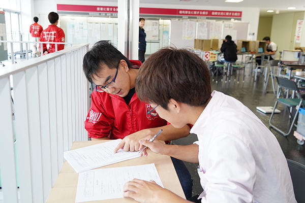 赤いジャンパーを着た学生自治会献血会のメンバーが呼び込みや問診票の記入をサポート。献血者をスムーズに誘導します。